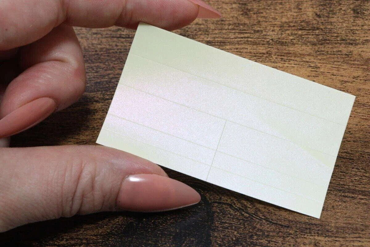 女性がパステルカラーの反射ラベルを指でつまんで見せている 女性がパステルカラーの反射ラベルを指でつまんで見せている