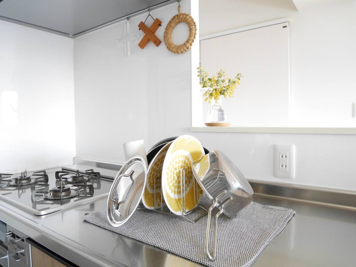 白いキッチンのカウンターにティータオルを敷いてスタンドにお皿や鍋蓋を立てかけたすっきりとした水切りの様子 白いキッチンのカウンターにティータオルを敷いてスタンドにお皿や鍋蓋を立てかけたすっきりとした水切りの様子