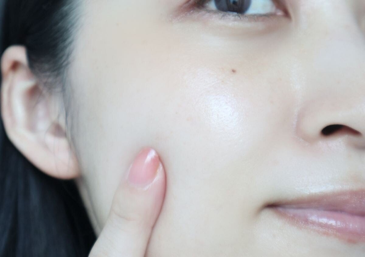美容液使用後のなめらかでツヤのある頬に触れる様子 美容液使用後のなめらかでツヤのある頬に触れる様子