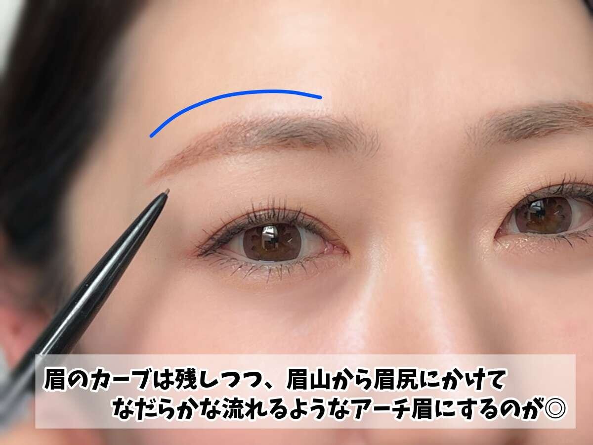 眉ペンシルで眉を描き、なだらかなアーチ眉のラインを青い線で示している女性の顔のアップ