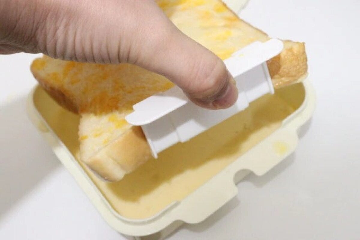 ダイソーのフレンチトーストメーカーのバスケットを使って卵液をしみ込ませたパンを引き上げる