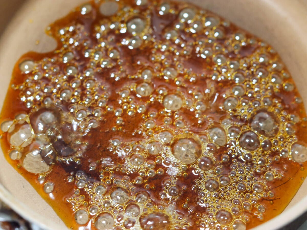 砂糖が琥珀色に色づき熱湯を加えて泡立っているカラメルソース