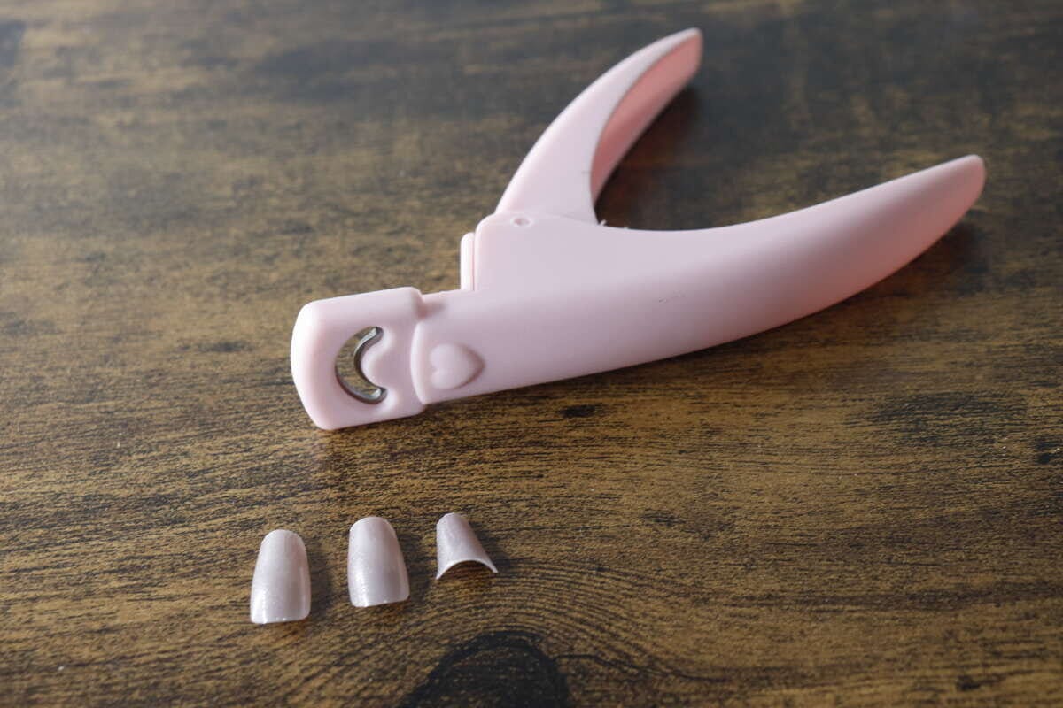ピンク色のネイルクリッパーとカット済みのネイルチップ3つ