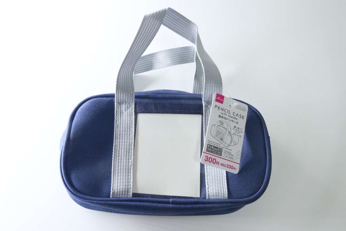 ネイビーの取手付ペンケースと商品タグ