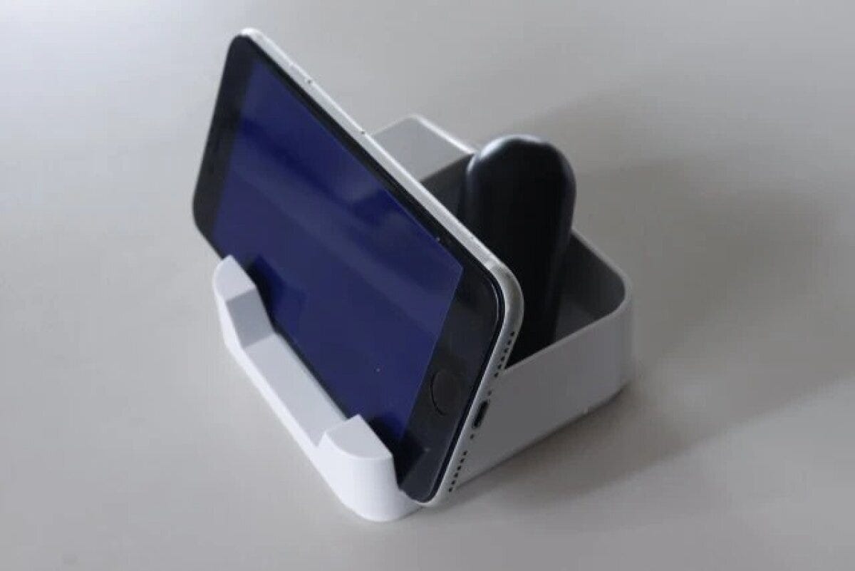 白い卓上収納ケースに横向きのスマートフォンと黒いペンが収納されている