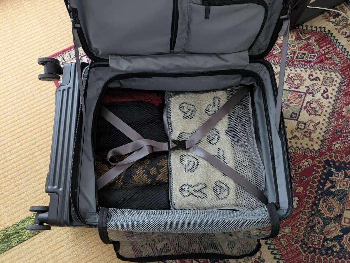 開いた黒いスーツケースに荷物が詰められた旅行グッズを出し入れする俯瞰写真