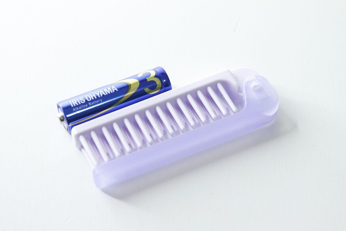 単3形乾電池と並べられた紫色の折りたたみヘアブラシ