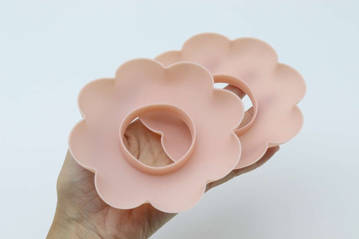 手のひらにピンクの花形洗顔リストバンド2個を重ねて持つ