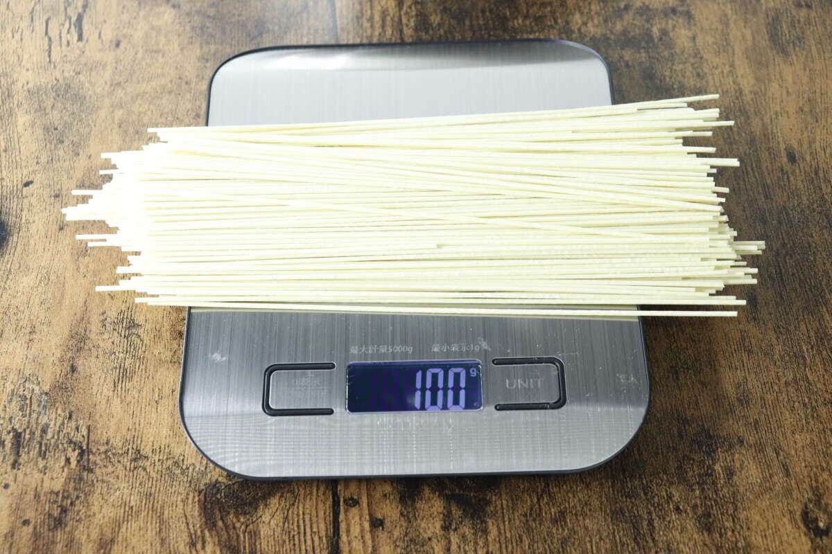 デジタルスケールの上に棒ラーメンの麺が100g計量されている様子 デジタルスケールの上に棒ラーメンの麺が100g計量されている様子