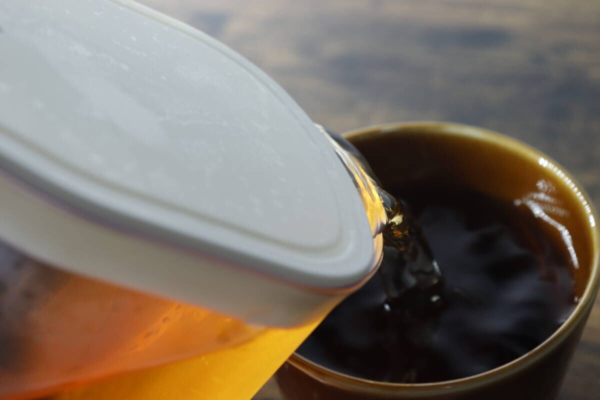 ピッチャーから茶色い飲み物をコップに注いでいる ピッチャーから茶色い飲み物をコップに注いでいる