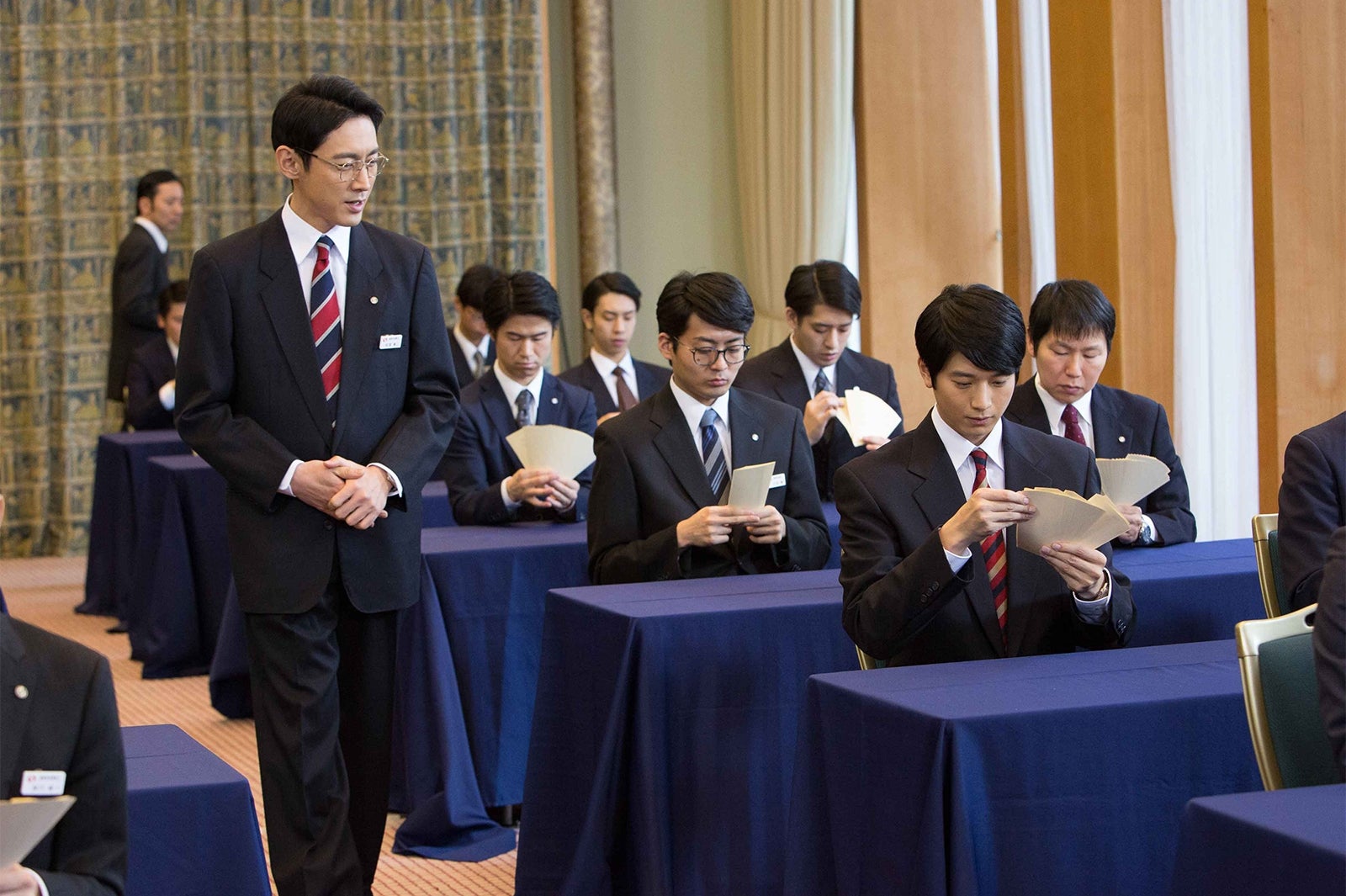 産業中央銀行新人研修時、札勘の練習をする階堂彬（向井理）を見守る安堂章二（小泉孝太郎）／画像提供：WOWOW