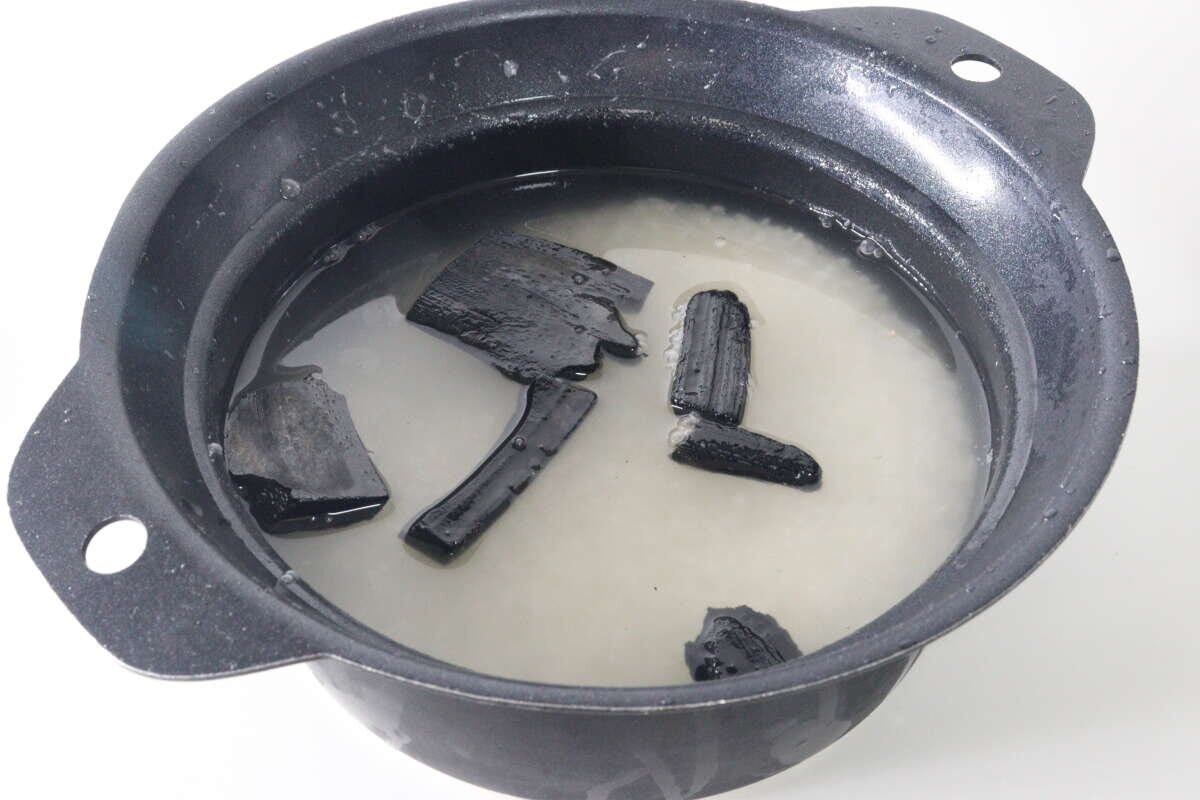 炊飯器の釜に米と水、そして竹炭が数個入っている様子