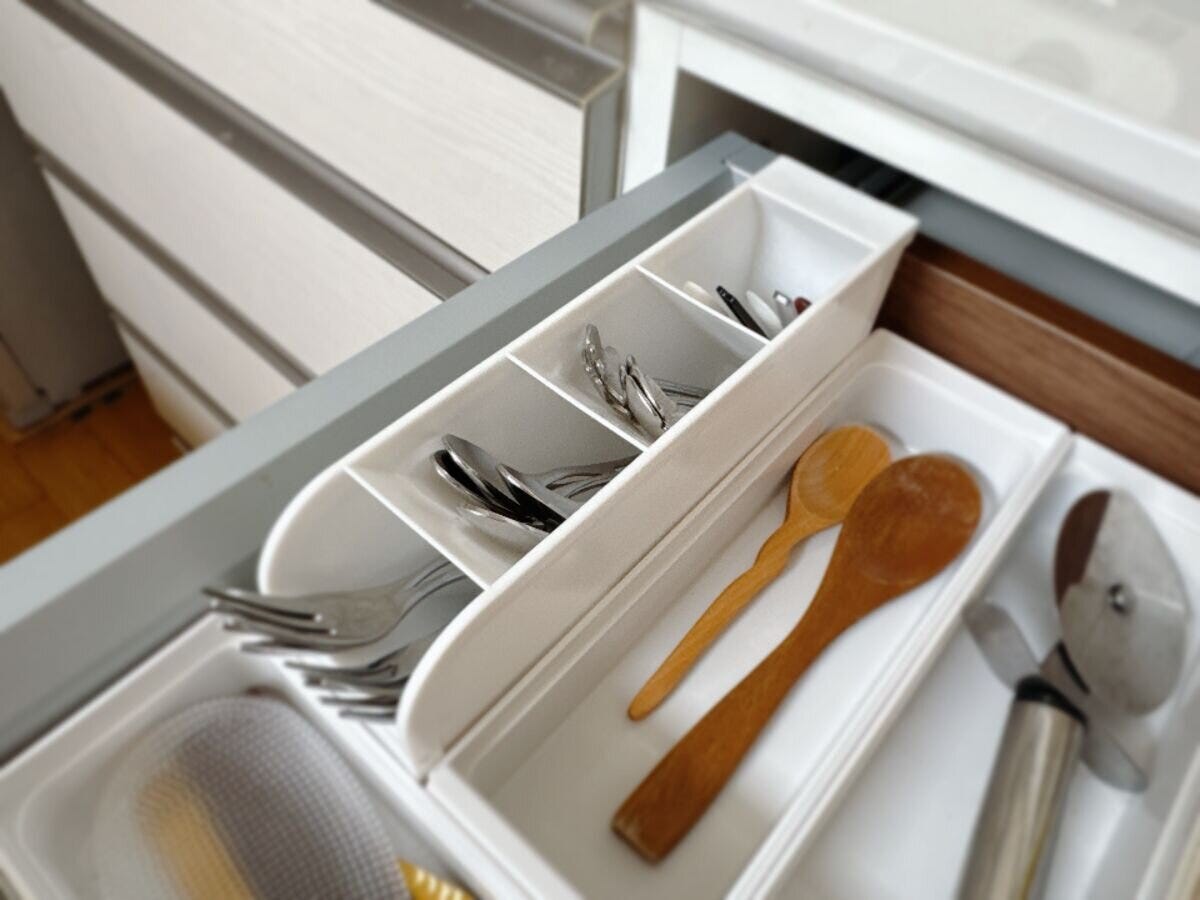 キッチンの引き出しに白いスタンドを横向きに寝かせスプーンやフォークが仕切りごとに収納されている