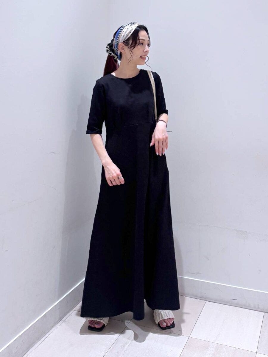 黒いフレアワンピースを着た女性、頭にスカーフを巻いて横向き