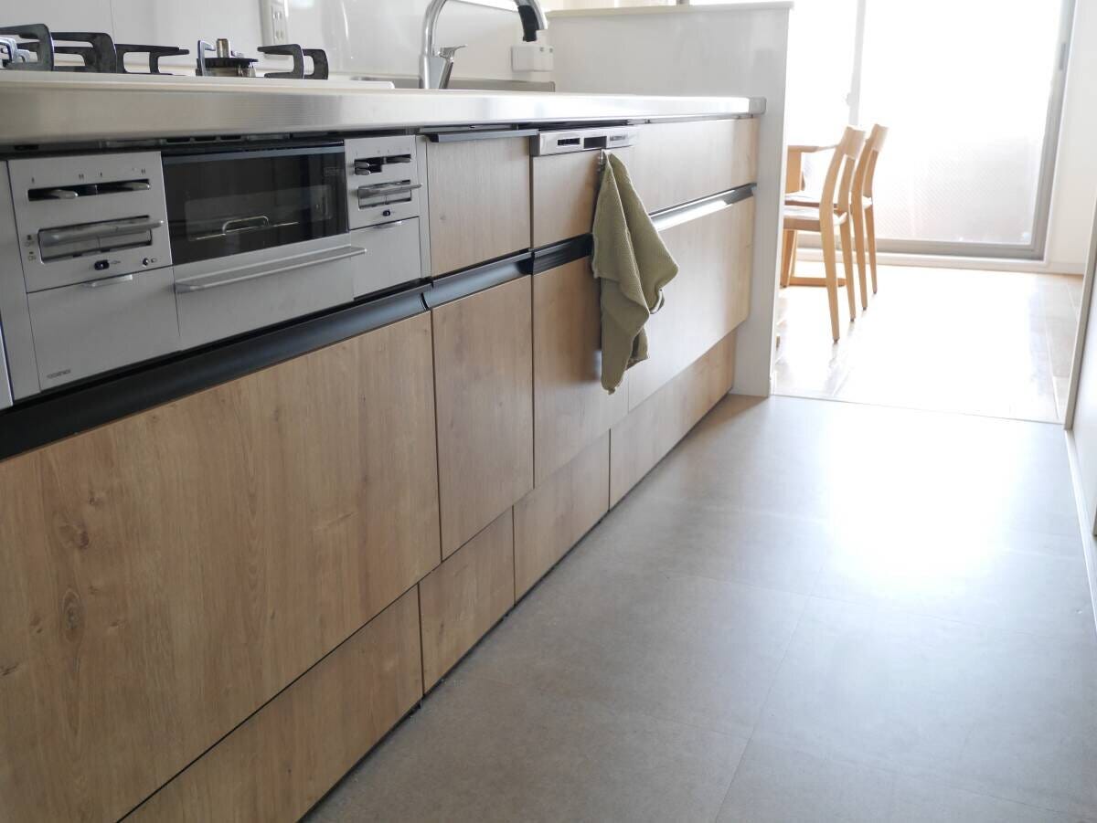 キッチンマットなしで白い床タイルがすっきりと見える木目調キャビネット前の様子 キッチンマットなしで白い床タイルがすっきりと見える木目調キャビネット前の様子