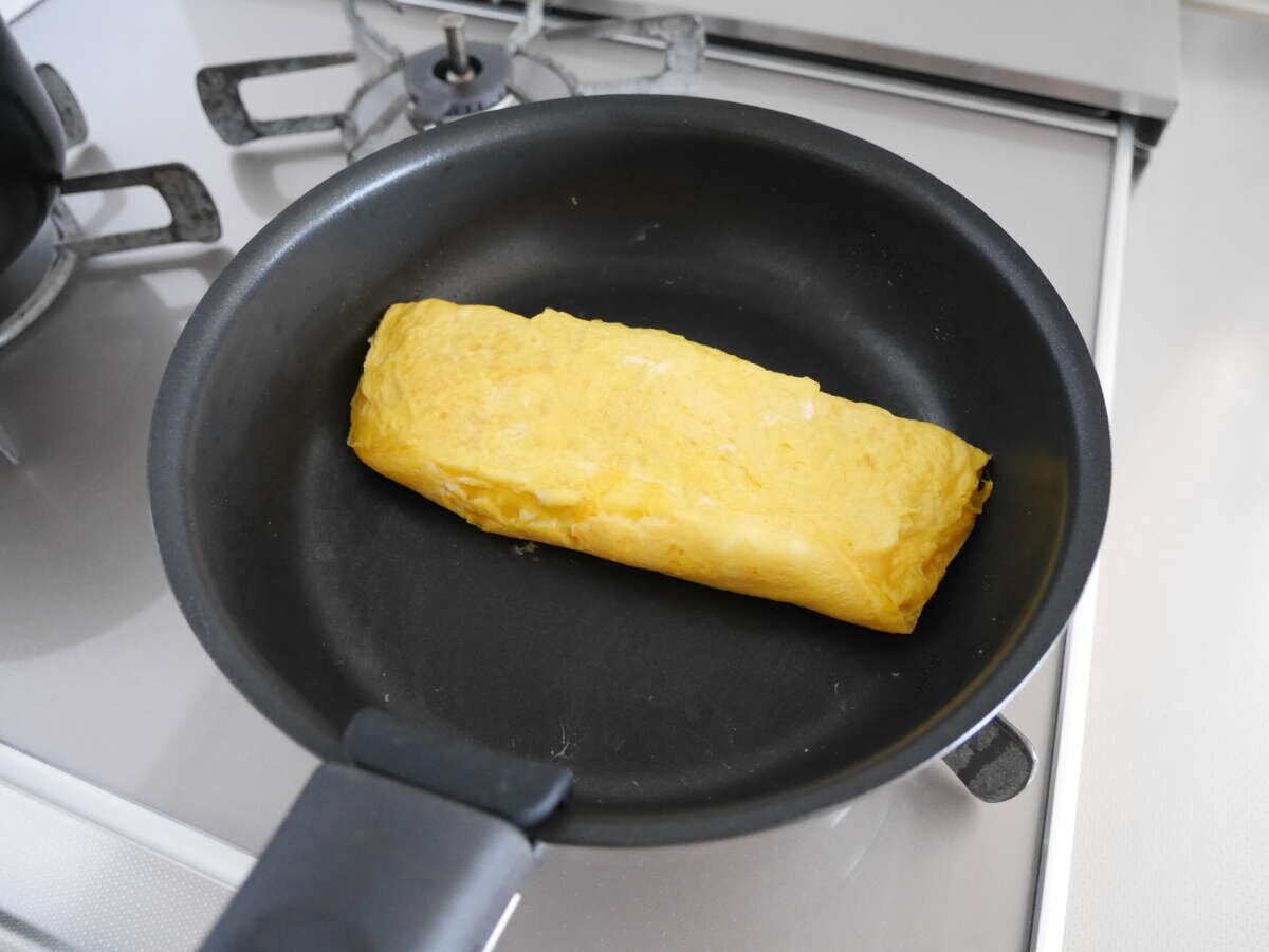 ガスコンロの上の黒い丸いフライパンで卵焼きを焼いている様子 ガスコンロの上の黒い丸いフライパンで卵焼きを焼いている様子