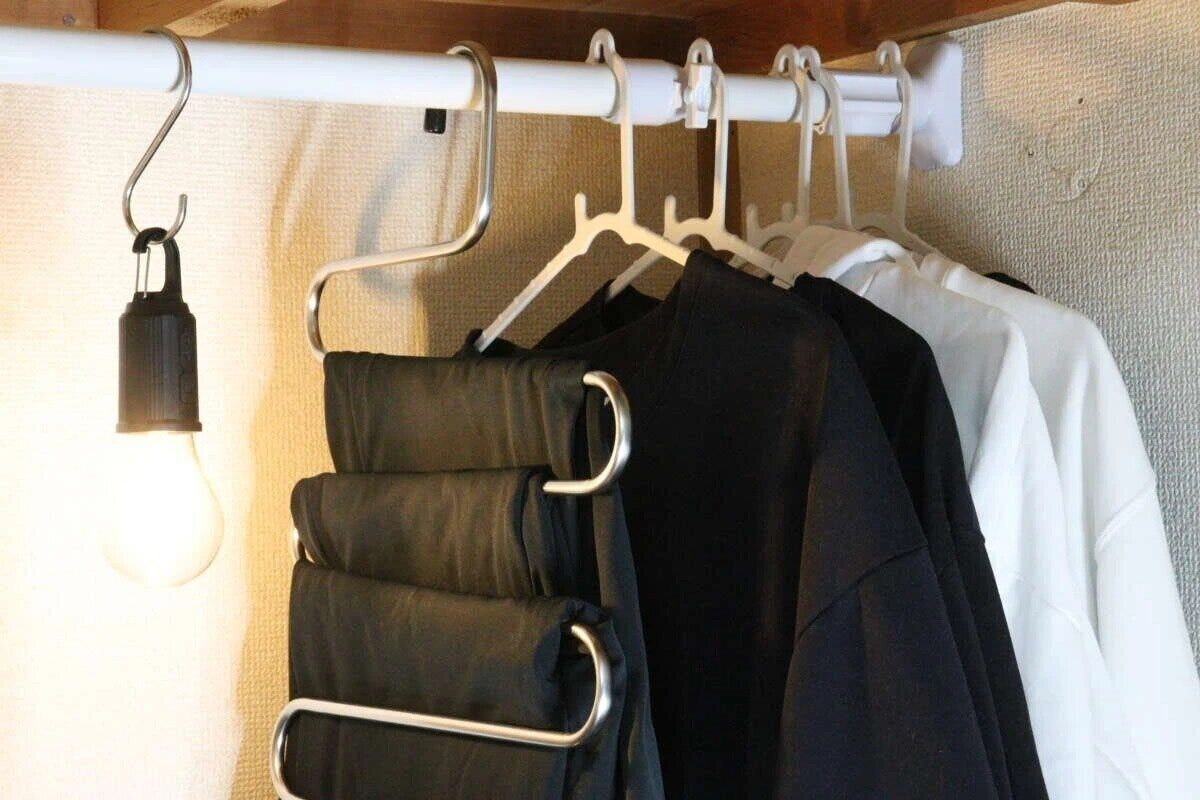 つっぱり棒に吊るされた黒と白の服、S字フックの電球 つっぱり棒に吊るされた黒と白の服、S字フックの電球
