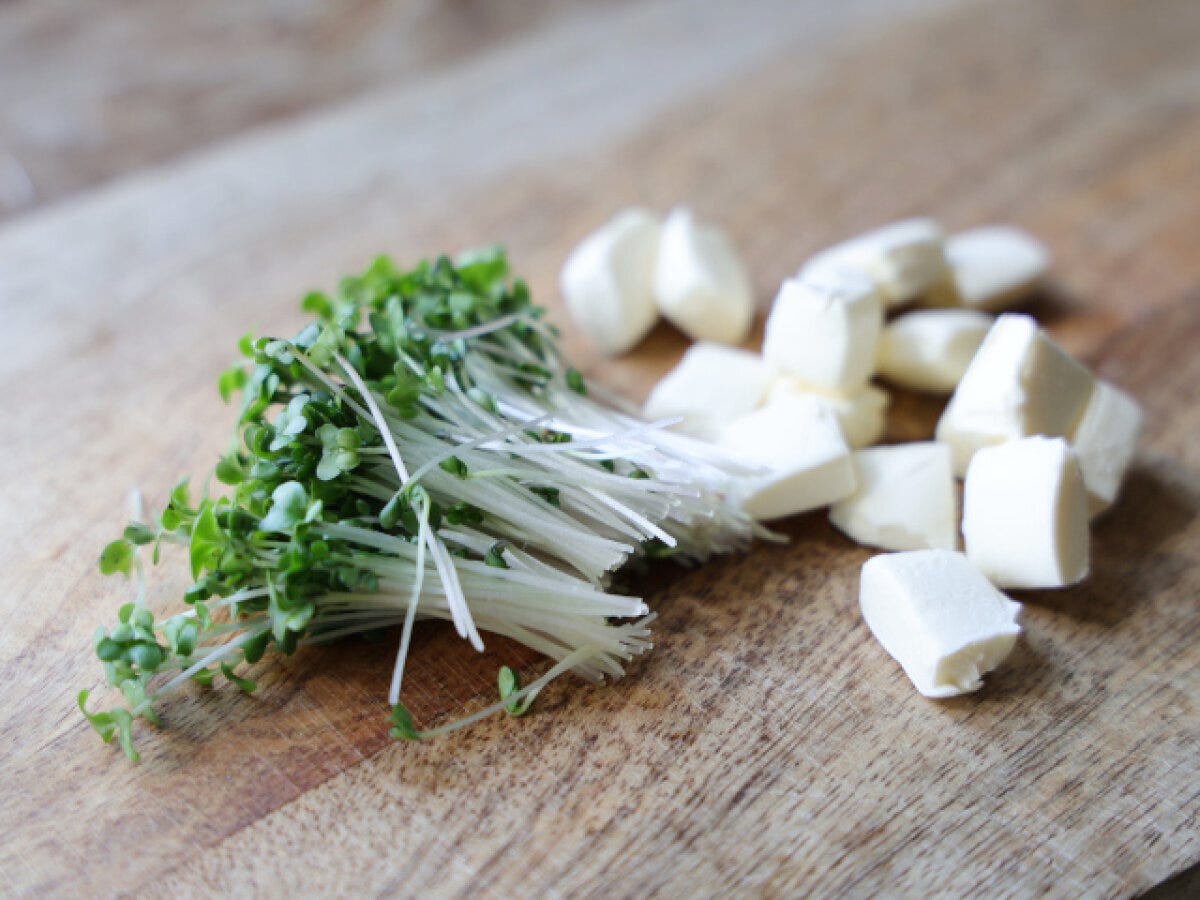 まな板の上に並べたブロッコリースプラウトと角切りのクリームチーズ まな板の上に並べたブロッコリースプラウトと角切りのクリームチーズ