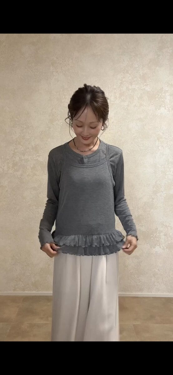 グレーのキャミソールとアイボリーのワイドパンツを着用した女性