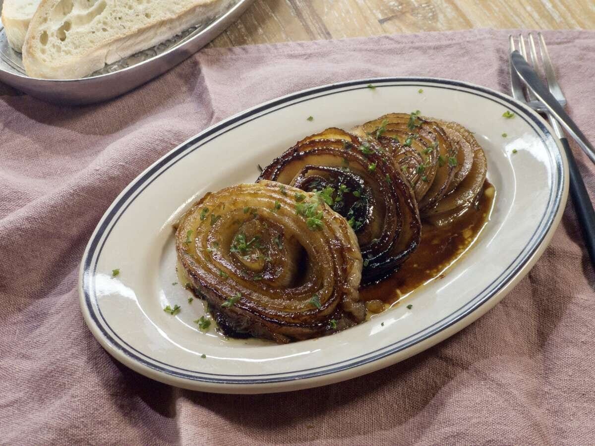 白いオーバル皿にビネガーバター醤油ソースをからめたパセリ散らしの新玉ねぎステーキ4枚の完成品