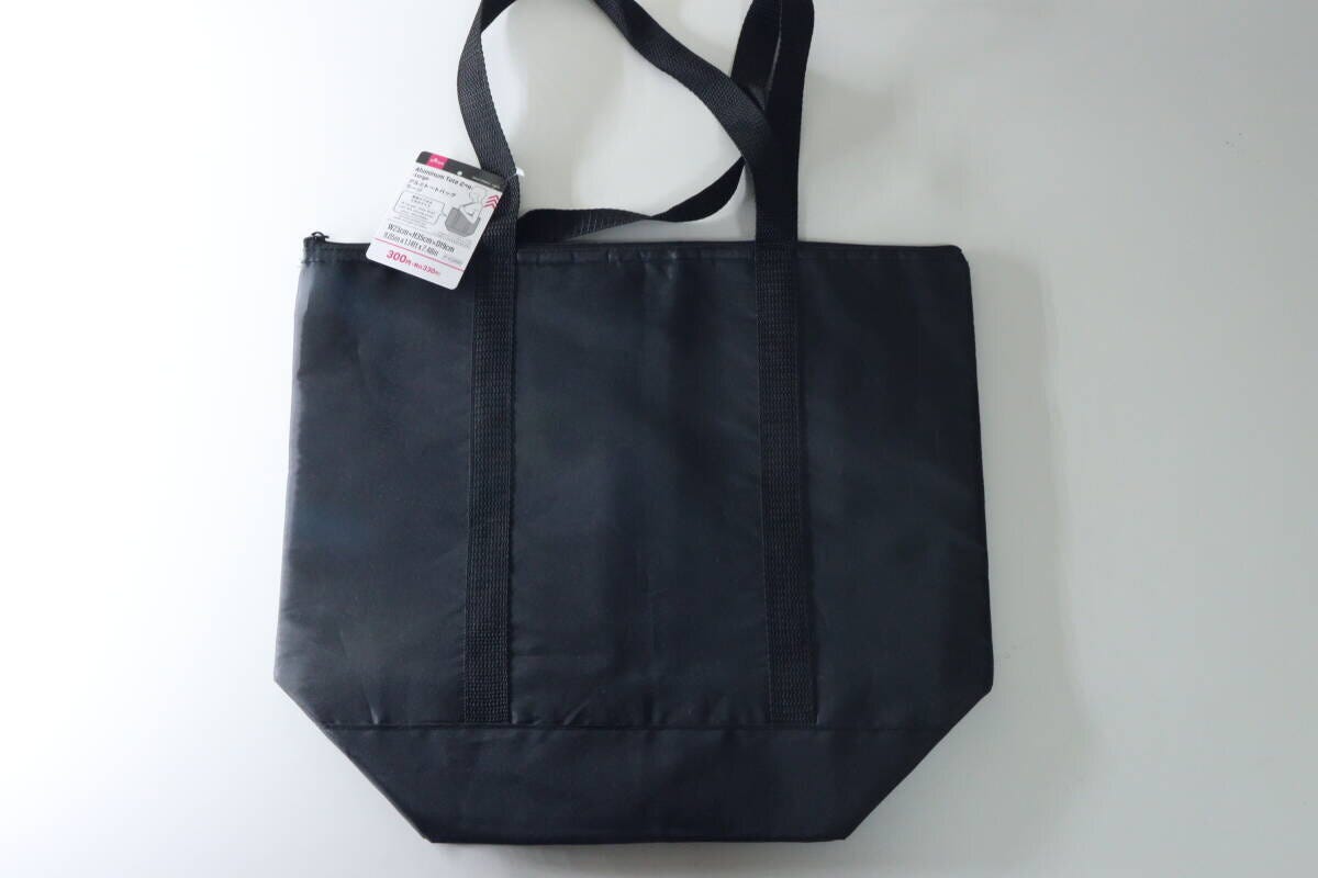 黒いアルミトートバッグが平置きされており、商品タグが付いている