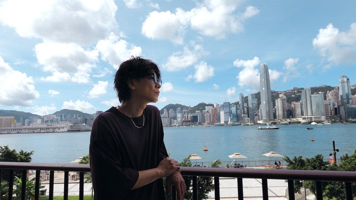 ビクトリア・ハーバー越しに香港を象徴する高層ビル群を望む佐藤健／提供画像