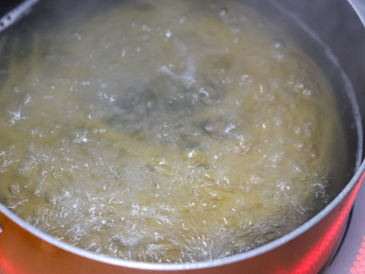 大鍋の沸騰した湯でスパゲッティを茹でている工程のクローズアップ写真