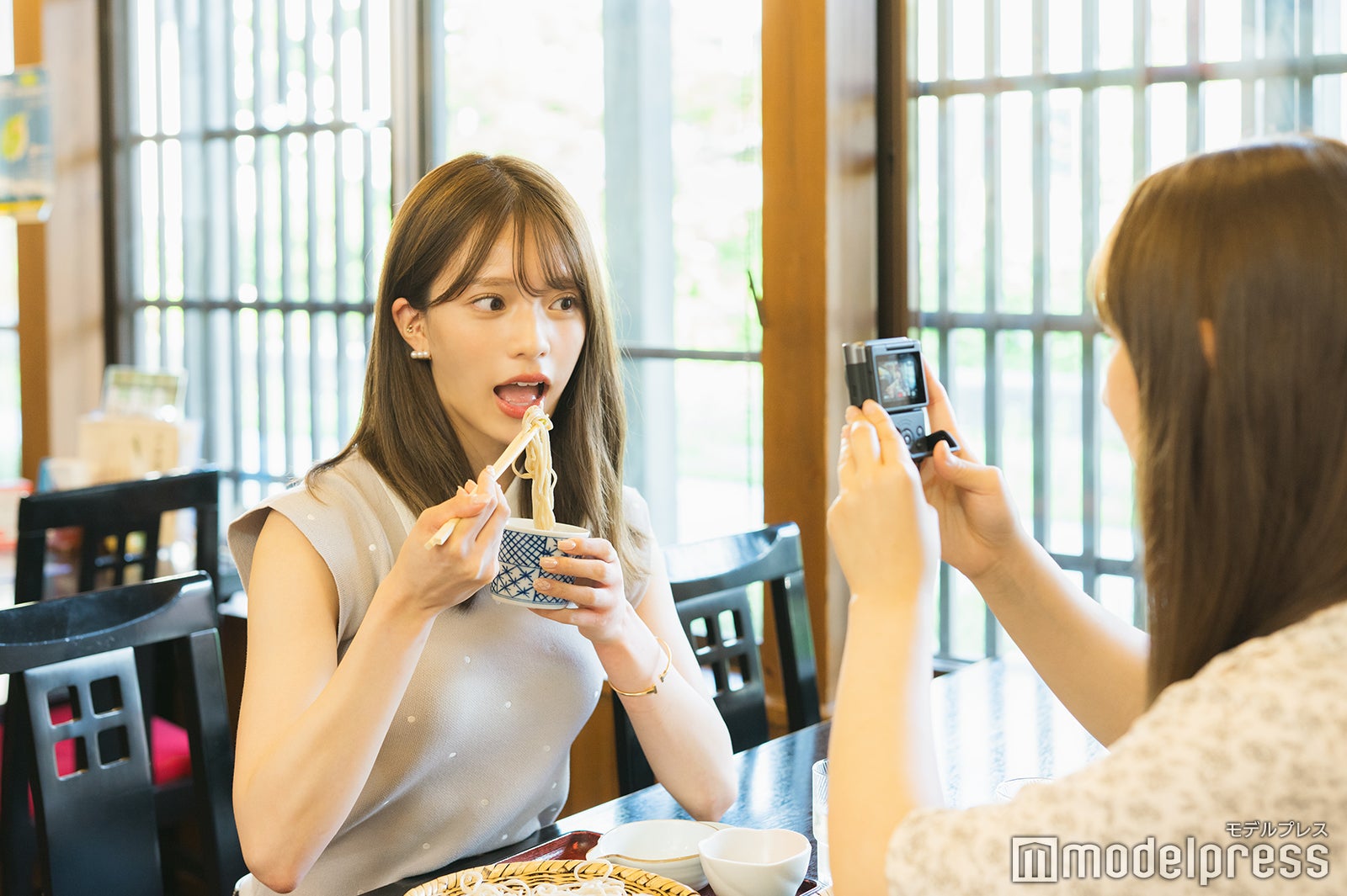 そばを食べている藤田みりあを撮影する與儀ケイラ（C）モデルプレス