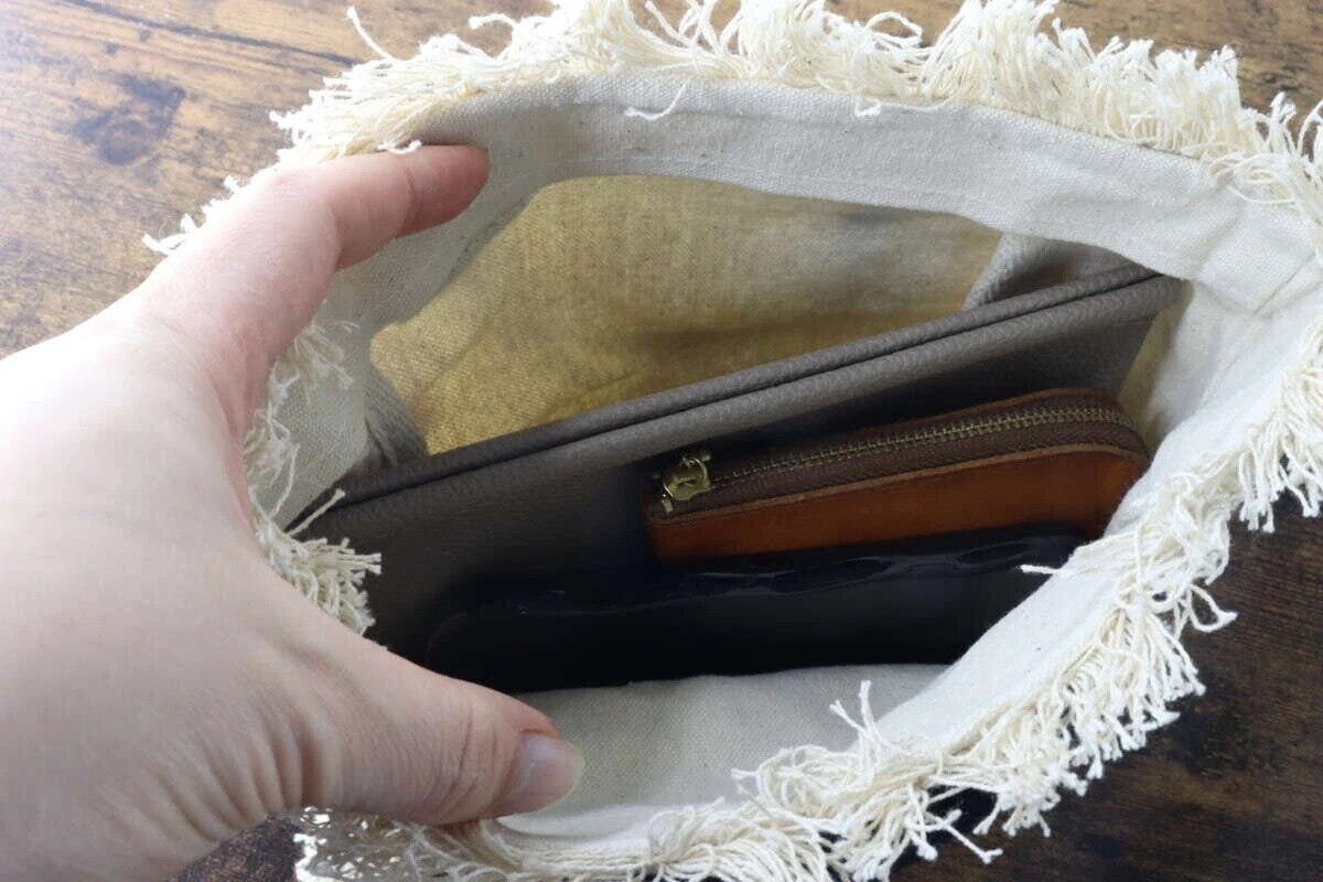 フリンジトートバッグの中に財布やポーチを入れている手元