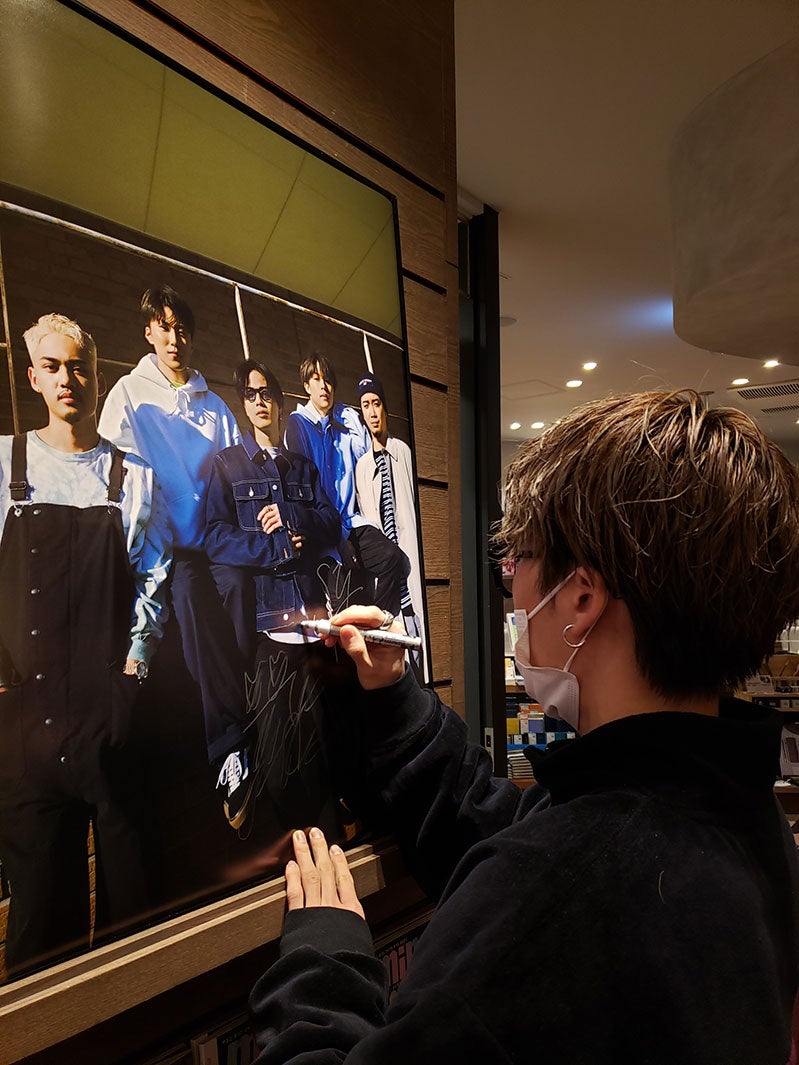 サインを書くコムドットメンバー（画像提供：宝島社）