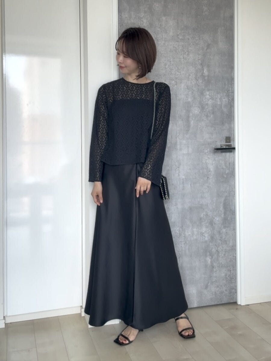 黒いレースブラウスと黒いスカートのワントーンコーデの女性