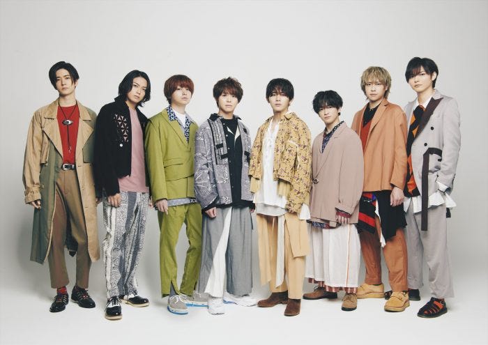 カラフルな衣装で並ぶ8人組の男性