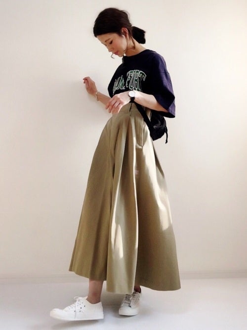 ネイビーのロゴTにベージュのチノスカートを履いた女性