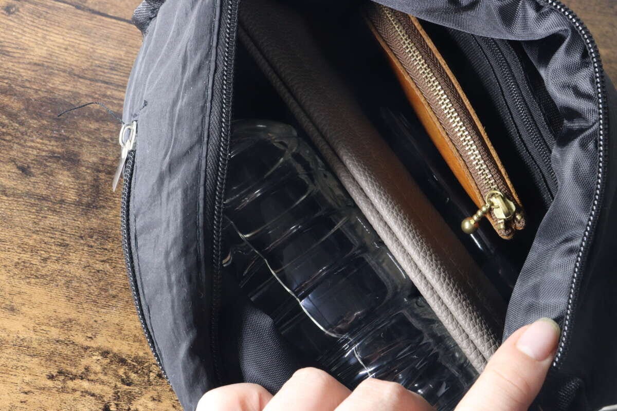 黒いバッグのメイン収納にペットボトルや長財布、コインケースが入っている