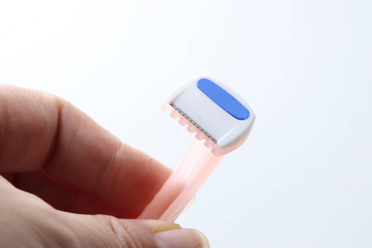指で持ったビキニライン用カミソリのヘッド部分のアップ 指で持ったビキニライン用カミソリのヘッド部分のアップ
