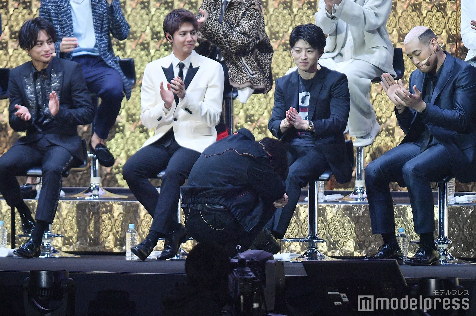 告白披露後、恥ずかしくなりうずくまる川村壱馬（前）と称える先輩たち（後ろ）（C）モデルプレス