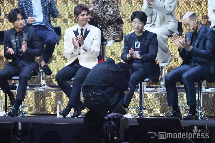 告白披露後、恥ずかしくなりうずくまる川村壱馬(前)と称える先輩たち(後ろ)(C)モデルプレス