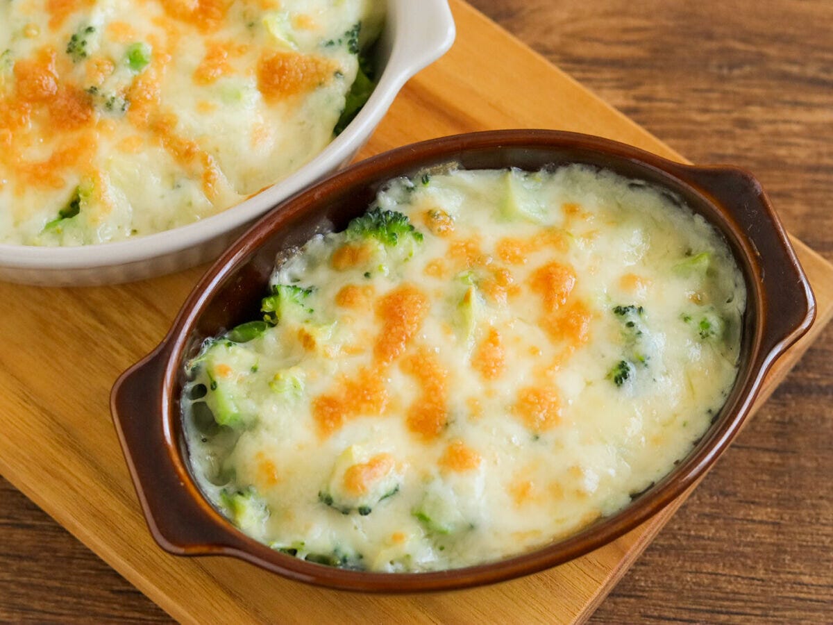 木のトレイに乗った2皿のブロッコリーグラタンでチーズが溶けて焦げ目がついた完成品 木のトレイに乗った2皿のブロッコリーグラタンでチーズが溶けて焦げ目がついた完成品