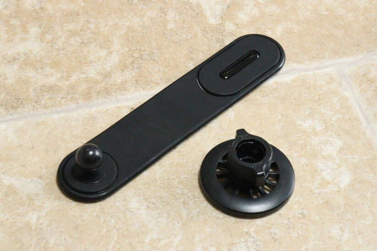 黒いマグネット式スマホホルダーのパーツ2点が床に置かれている 黒いマグネット式スマホホルダーのパーツ2点が床に置かれている