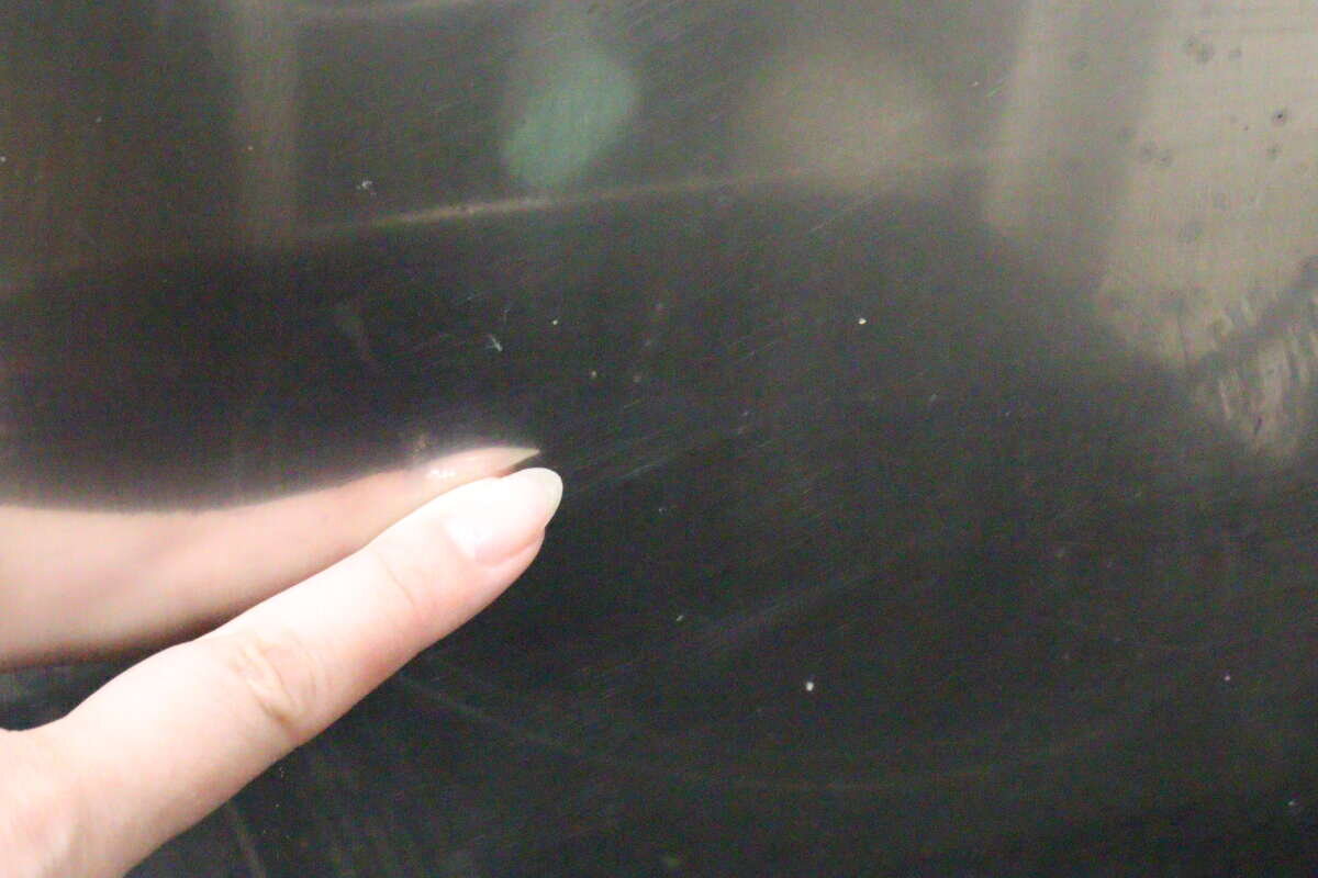 油汚れが点々と付着したコンロの表面を指で指している