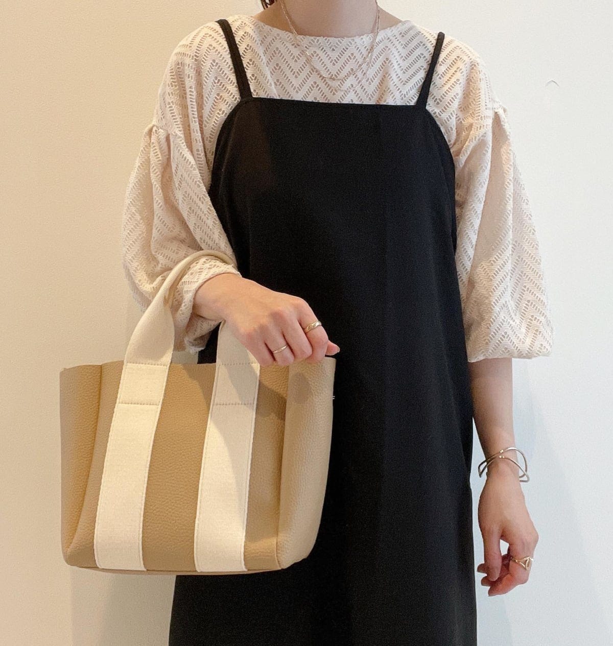 ブラックキャミワンピとホワイトトップスを着ている女性