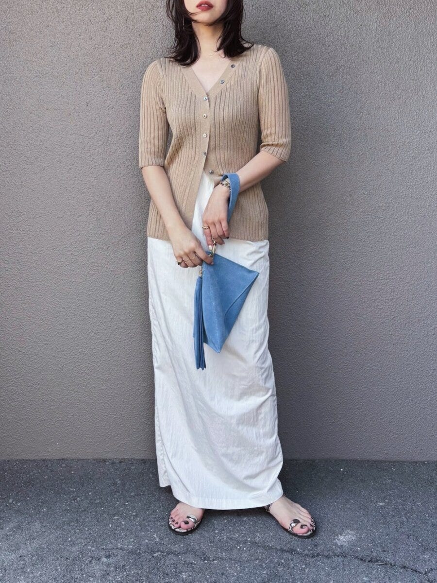 ベージュカーデと白ナロースカート、青いバッグを持つ女性 ベージュカーデと白ナロースカート、青いバッグを持つ女性