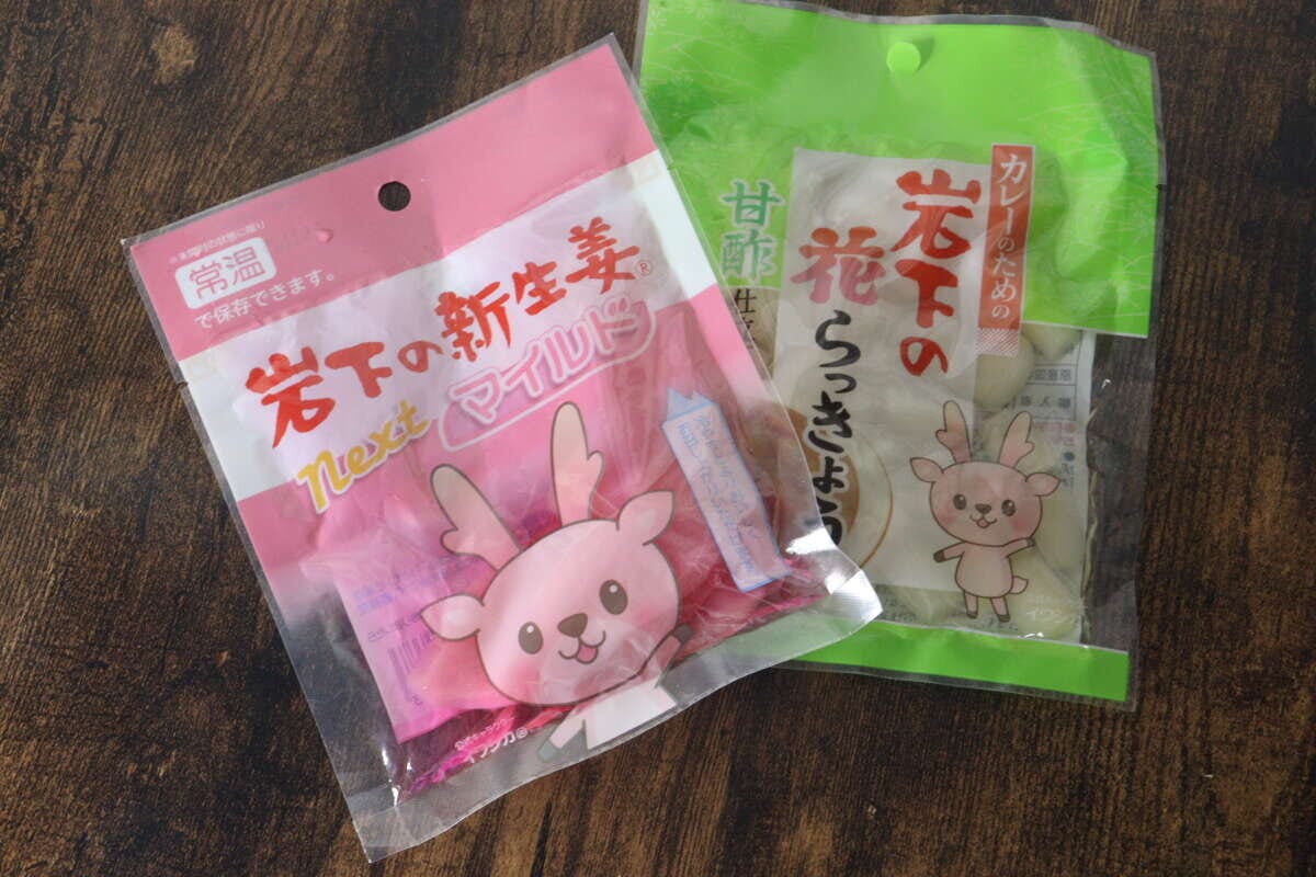 ピンクと緑のパッケージに入った岩下の新生姜と花らっきょうが並んで斜めに置かれている ピンクと緑のパッケージに入った岩下の新生姜と花らっきょうが並んで斜めに置かれている