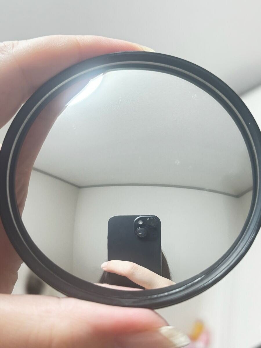 自転車用バックミラーに黒いスマートフォンと指が映り込んでいる 自転車用バックミラーに黒いスマートフォンと指が映り込んでいる