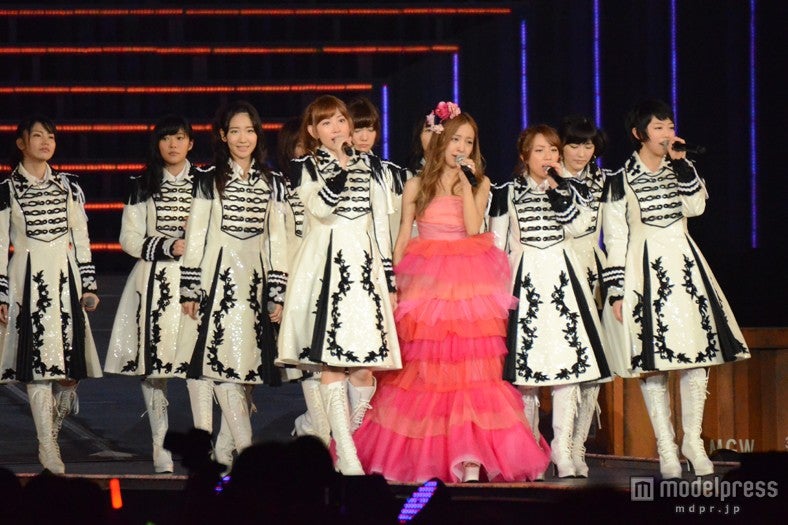 溢れ出る涙をこらえながらメンバーに囲まれ歌唱する板野友美