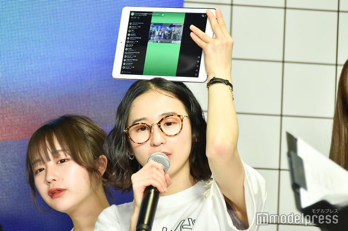 配信のコメントを見せながら歌うめがね (C)モデルプレス