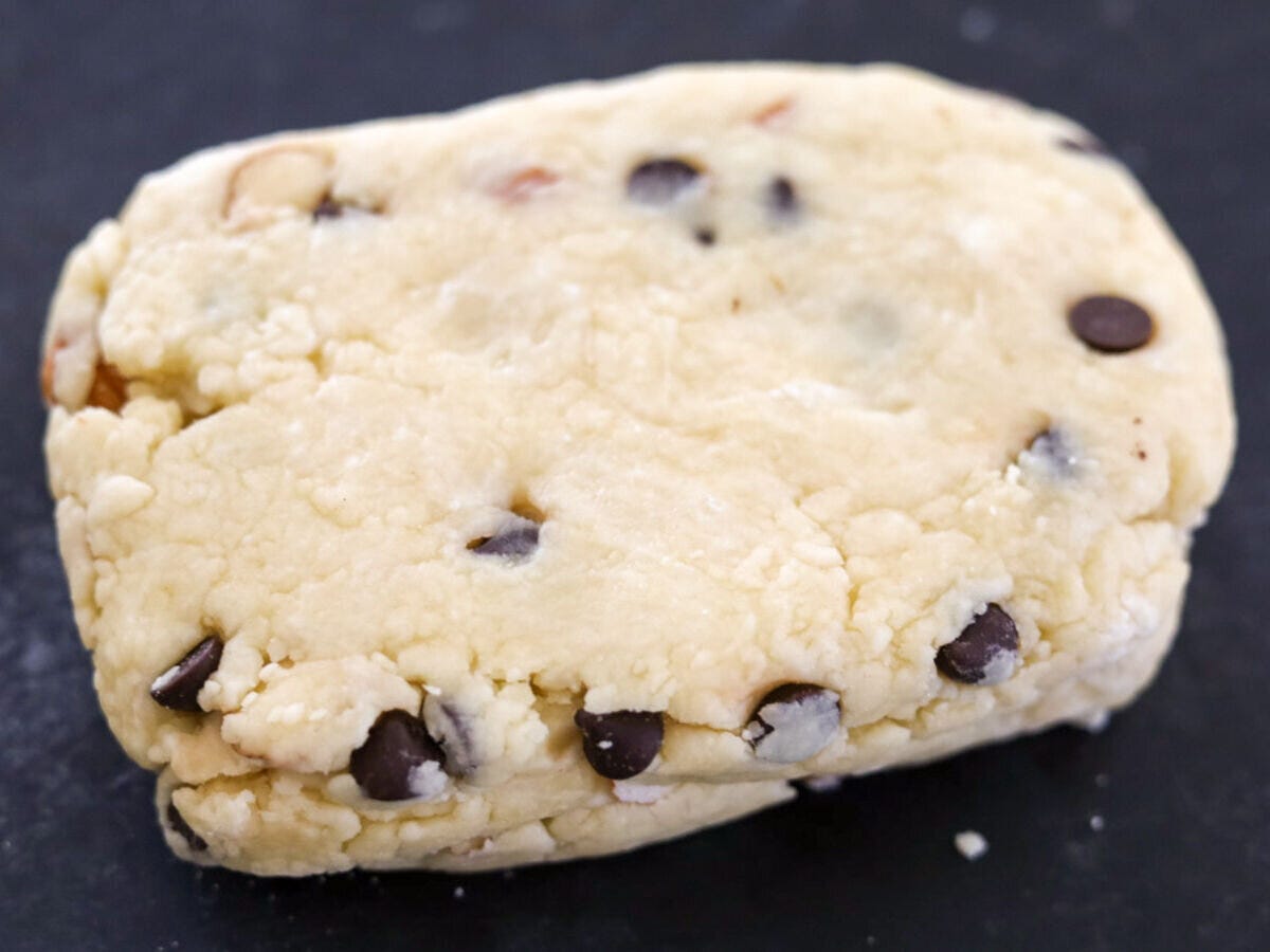 チョコチップとアーモンドが入った生地をひとまとめにして黒い作業台に出した状態