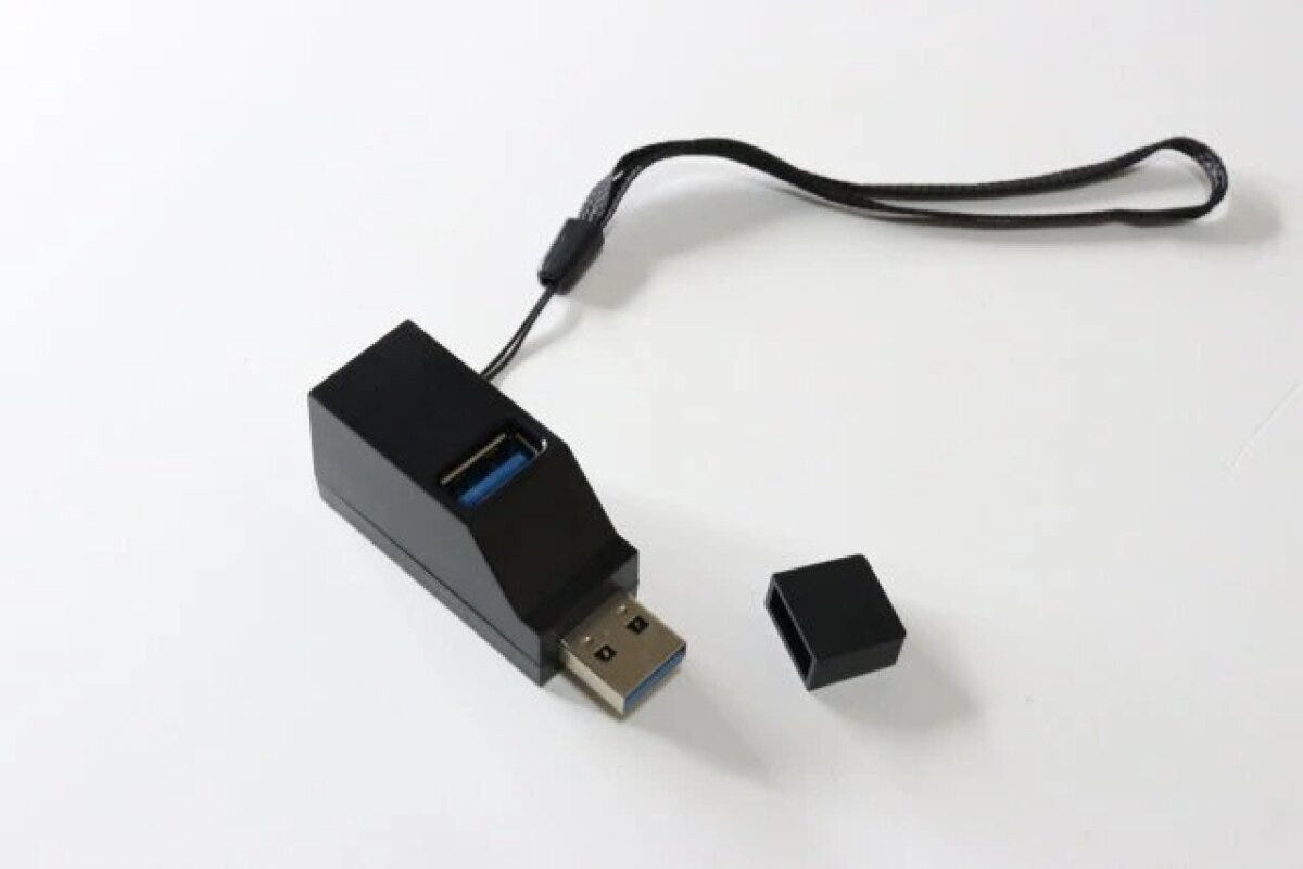黒いUSBハブがキャップを外して置かれ、ストラップが付いている