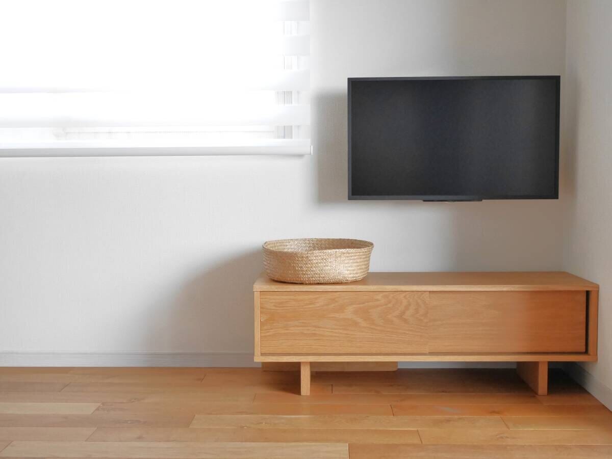 すっきりと片付いたテレビボードと壁掛けテレビがあるリビングの様子 すっきりと片付いたテレビボードと壁掛けテレビがあるリビングの様子