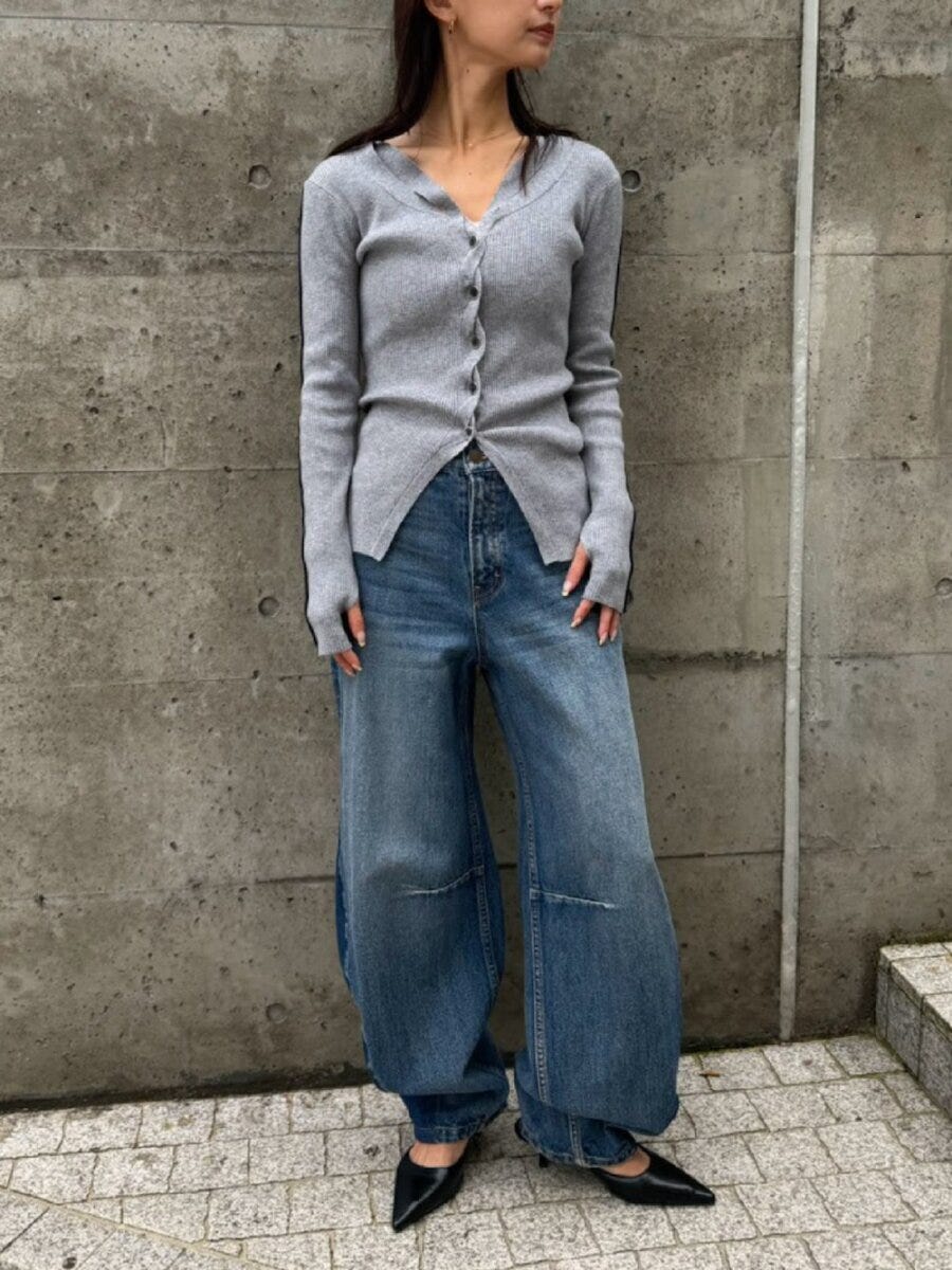 グレーのリブVネックカーディガンとライトブルーワイドデニムの女性